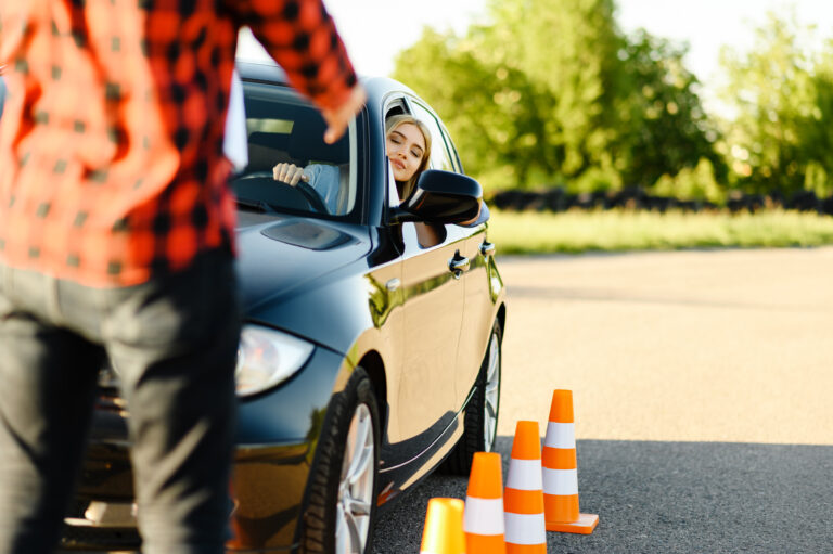 Male instructor and woman in car, traffic cones